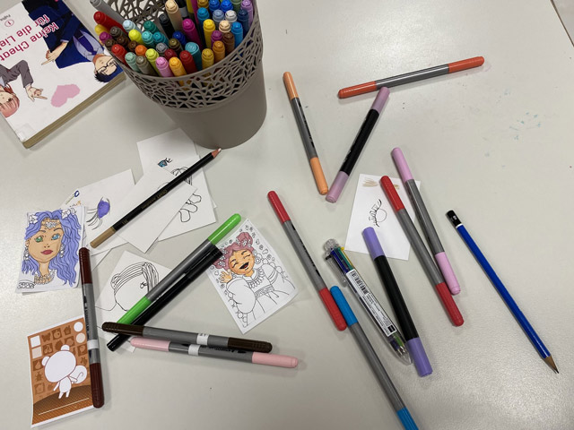 Nahaufnahme bunt bemalter KaKAO-Karten mit Manga-Motiven, ausgestellt auf einem Tisch.