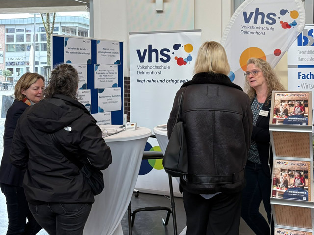 Mitarbeitende im Beratungssgespräch beim Stand der vhs auf dem Markt der Möglichkeiten in der Markthalle